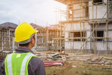 Asyalı işadamı inşaat mühendisi koruyucu miğfer ve bina inşaatında kullanılacak planlar.