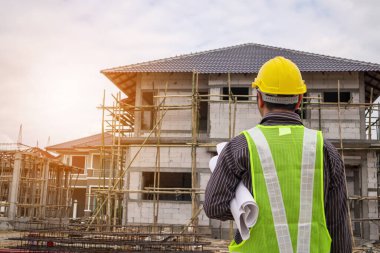 Asyalı işadamı inşaat mühendisi koruyucu miğfer ve bina inşaatında kullanılacak planlar.