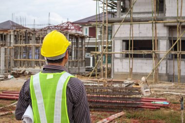 Asyalı işadamı inşaat mühendisi koruyucu miğfer ve bina inşaatında kullanılacak planlar.