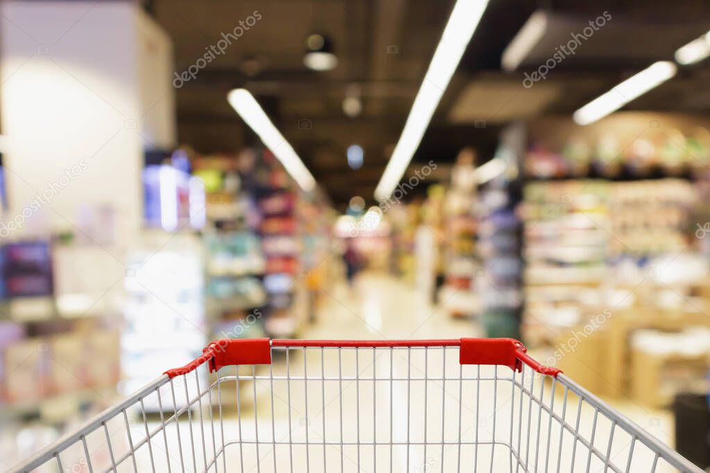 blur supermarket aisle with empty red shopping cart background