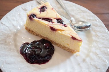beyaz tabakta ahşap masada yabanmersinli cheesecake