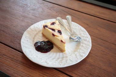 beyaz tabakta ahşap masada yabanmersinli cheesecake