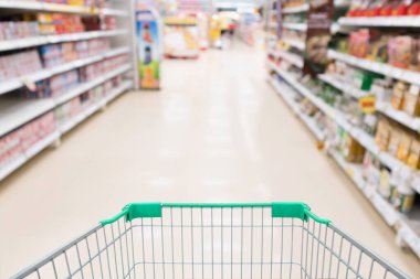 Boş yeşil alışveriş arabası olan süpermarket koridoru ürün rafları müşteri arkaplanından çıkarıldı