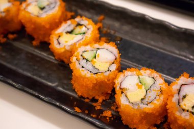 Kaliforniya maki suşisi siyah tabakta, Japon yemeği.