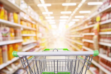 Süpermarket koridoru ürün rafları içi bulanık arka plan ve boş alışveriş arabası 