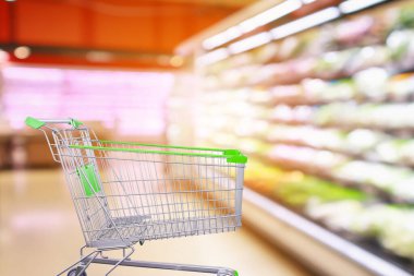 Taze sebzeler ve meyve raflarıyla süpermarket koridoru içi boş alışveriş arabasıyla bulanık arka plan