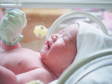 Yeni doğmuş bebek hastanedeki kuvözde uyuyor.