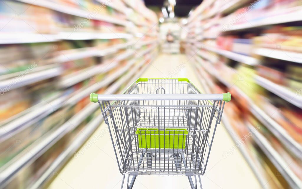 Supermarket aisle with empty green shopping cart in motion blur abstract background