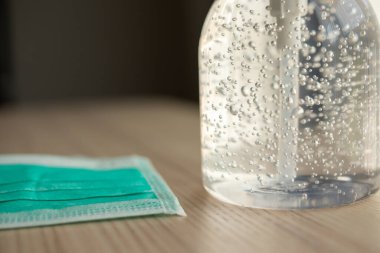 Covid-19 Coronavirus önleme konsepti için ahşap masaya alkol dezenfektanlı yüz maskesi.