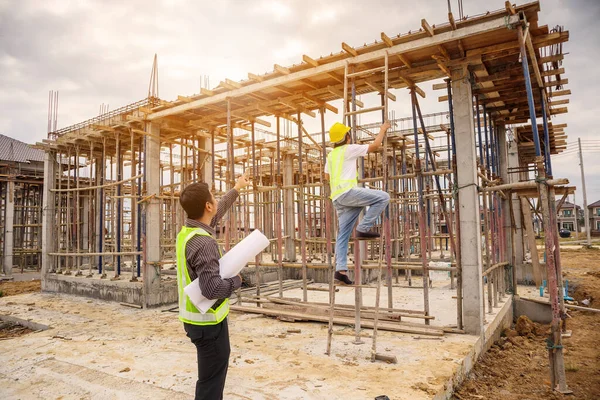 亚洲商人 建筑经理和戴防护头盔的工程师在建筑工地拿着设计图纸 — 图库照片