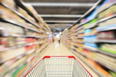 Süpermarket koridoru rafları olan kırmızı alışveriş arabası görünümü soyut bulanık arka plan