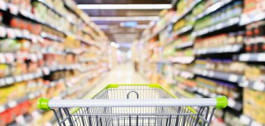 Market koridoru, içi ürün raflarıyla dolu boş yeşil alışveriş arabası soyut bulanık arkaplan