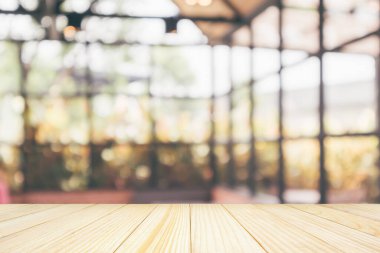 Boş ahşap masa üstü, kafeterya kahvesi, iç mekan, soyut bulanıklık, montaj ürünü gösterimi için bokeh ışığı arkaplanı.