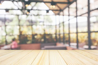 Boş ahşap masa üstü, kafeterya kahvesi, iç mekan, soyut bulanıklık, montaj ürünü gösterimi için bokeh ışığı arkaplanı.