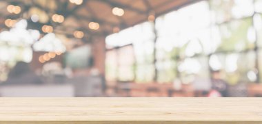 Kafe restoranı ya da kahve dükkanı penceresi olan boş ahşap masa üstü ya da montaj ürün gösterimi için bokeh ışığı arka planına odaklanmış soyut bulanıklık.