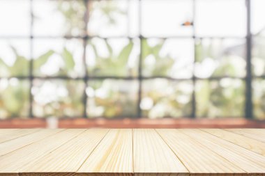 Kafe restoranı ya da kahve dükkanı penceresi olan boş ahşap masa üstü ya da montaj ürün gösterimi için bokeh ışığı arka planına odaklanmış soyut bulanıklık.