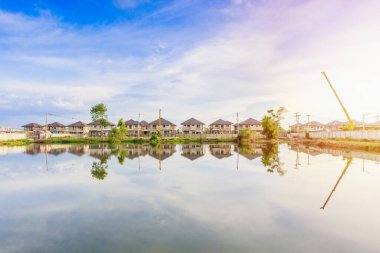 Yeni ev binası yansıması gölde suyla birlikte bulutlu ve mavi gökyüzü olan konut inşaat sahasında.