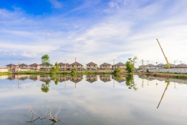 Yeni ev binası yansıması gölde suyla birlikte bulutlu ve mavi gökyüzü olan konut inşaat sahasında.