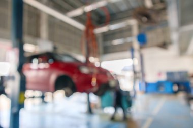 Otomotiv servis merkezindeki bakım istasyonunda kırmızı araba kaldırışı soyut arkaplan bulanıklığı