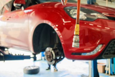 Otomotiv servis merkezindeki bakım istasyonunda kırmızı araba kaldırışı soyut arkaplan bulanıklığı