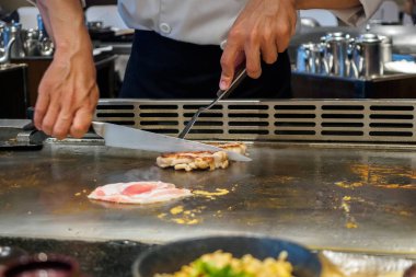 Japon şef Teppanyaki restoranında et pişiriyor.