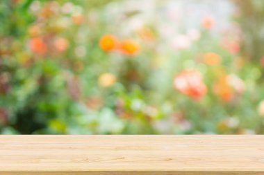 Bahçede soyut bulanık gül çiçekleri olan boş ahşap masa üstü ürün gösterimi için doğal bokeh ışığı arka planı