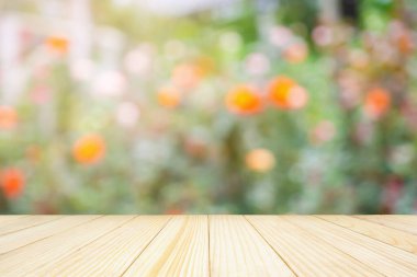 Bahçede soyut bulanık gül çiçekleri olan boş ahşap masa üstü ürün gösterimi için doğal bokeh ışığı arka planı