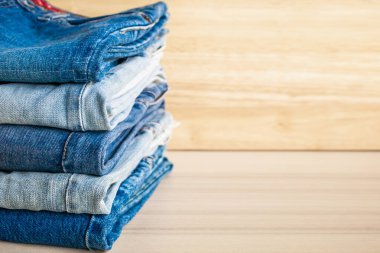 Ahşap arka planda kot pantolon yığını