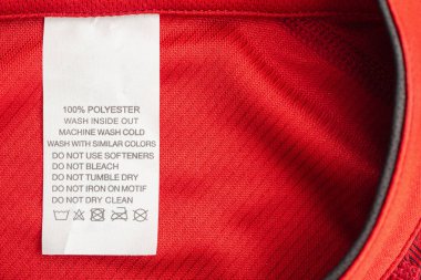 Kırmızı formalı polyester spor tişörtte beyaz çamaşır yıkama talimatları etiketi