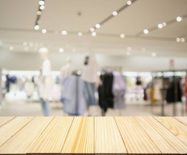 Boş ahşap masa ve alışveriş merkezindeki şık butik giyim mağazası vitrinleri.
