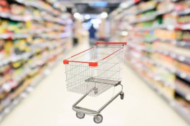 Soyut bulanık süpermarket indirim mağazası koridoru ve ürün rafları olan boş alışveriş arabası.