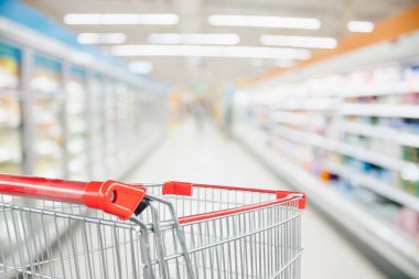 Süpermarket koridoru boş kırmızı alışveriş arabasıyla bulanık arka plan