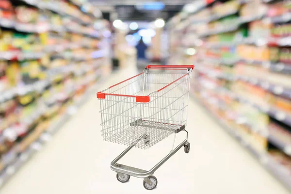Soyut bulanık süpermarket indirim mağazası koridoru ve ürün rafları olan boş alışveriş arabası.