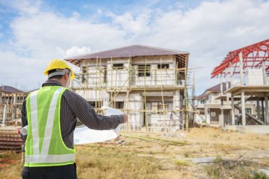 İnşaat alanının arka planında koruyucu mimar ve bina planları olan profesyonel mühendis.