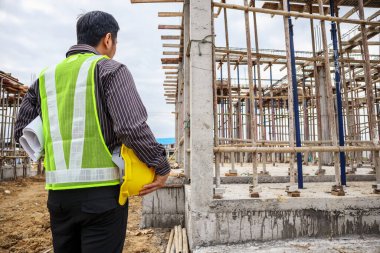 Asyalı işadamı inşaat mühendisi koruyucu miğfer ve bina inşaatında kullanılacak planlar.