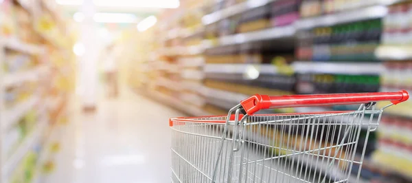 スーパーマーケットの通路を背景に空の赤いショッピングカート — ストック写真