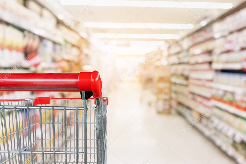 Empty shopping cart with abstract blur supermarket discount store aisle and product shelves interior defocused background