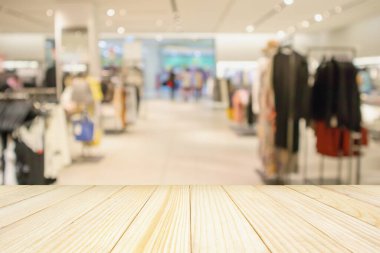 Boş ahşap masa ve alışveriş merkezindeki şık butik giyim mağazası vitrinleri.