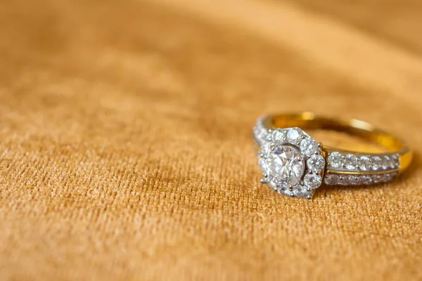 Jewelry diamond ring on golden fabric background close up