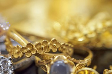 Siyah ve altın arkaplanda yansımalı lüks mücevher yüzükleri.