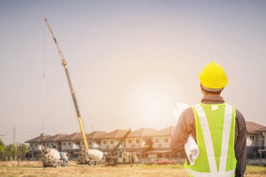 Asyalı işadamı inşaat mühendisi koruyucu miğfer ve bina inşaatında kullanılacak planlar.