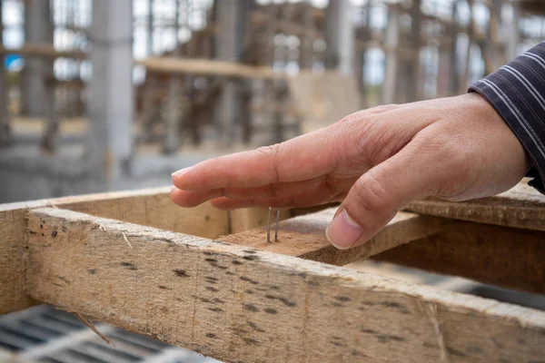 Construction worker hand on nail at house building site, work accident concept