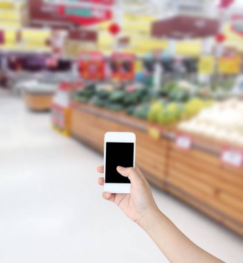 Sebzeli cep telefonu ve markette rafta duran meyve bulanık arka plan.