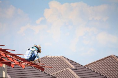 İnşaat işçileri binanın çatısının çelik iskelet yapısını inşa ediyorlar. İnşaat alanında bulutlar ve gökyüzü var.