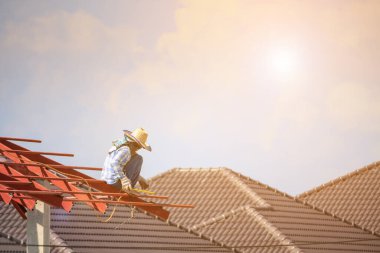 İnşaat işçileri binanın çatısının çelik iskelet yapısını inşa ediyorlar. İnşaat alanında bulutlar ve gökyüzü var.