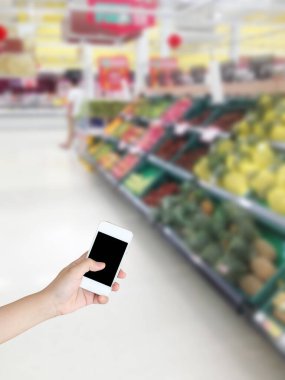 Sebzeli cep telefonu ve markette rafta duran meyve bulanık arka plan.