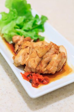 Teriyaki tavuğu beyaz tabakta kızartılıyor.