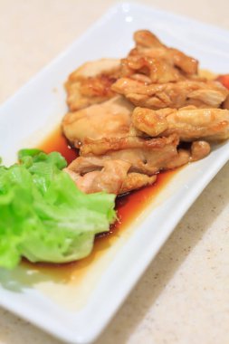 Teriyaki tavuğu beyaz tabakta kızartılıyor.