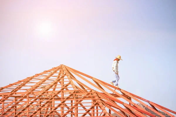 İnşaat işçileri binanın çatısının çelik iskelet yapısını inşa ediyorlar. İnşaat alanında bulutlar ve gökyüzü var.
