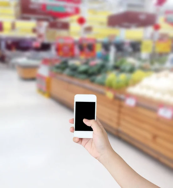 Mão Segurando Telefone Celular Com Legumes Frutas Prateleira Supermercado Desfocado — Fotografia de Stock